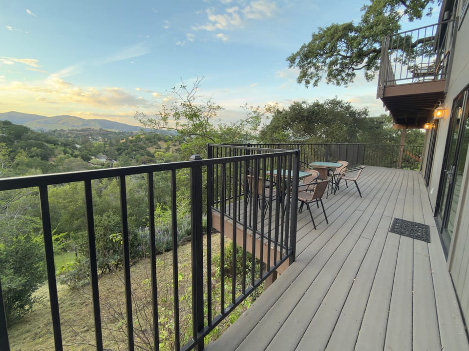 Lower deck with wraparound wicker seating and hillside views